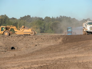 large machinery in the midst of construction activity on a large area of dirt