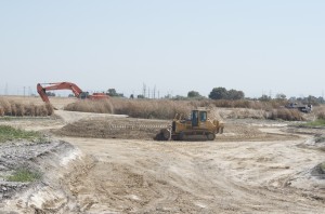  a bulldozer and a backhoe in operation to clear channels in the marshes