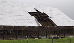 exterior view of a barn with a section of the roof damaged and missing