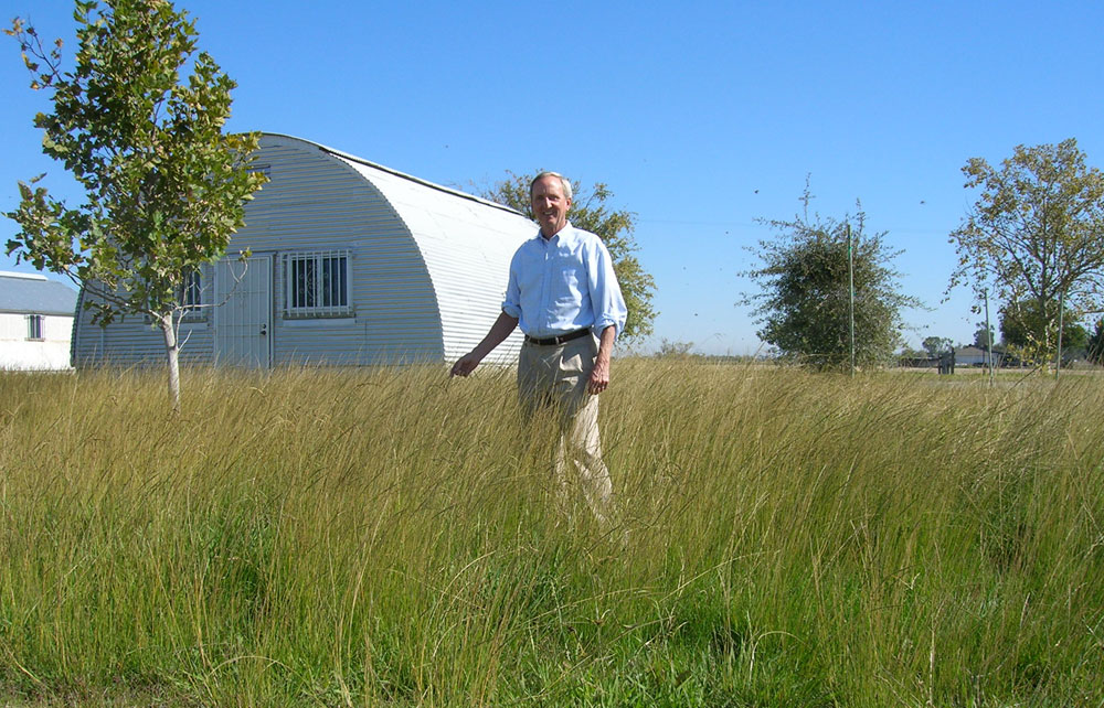 Ray Tretheway standing amongst needlegrass and smiling at the camera